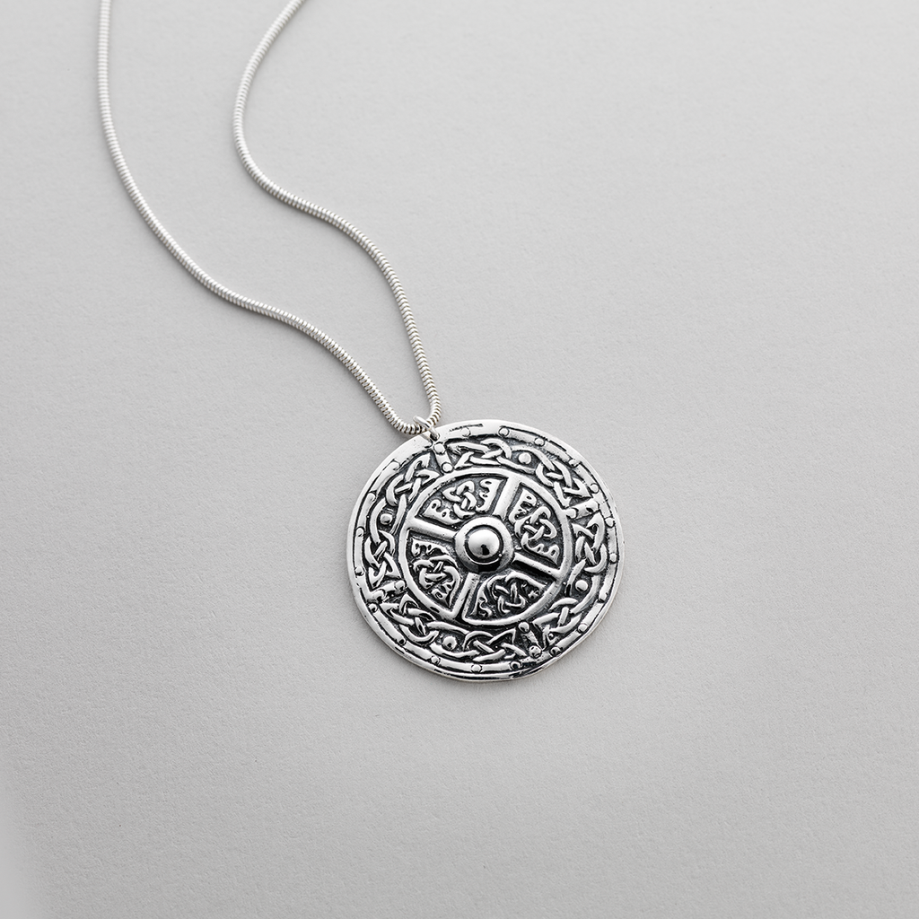 Circular silver pendant with Celtic design of intricate interlacements.