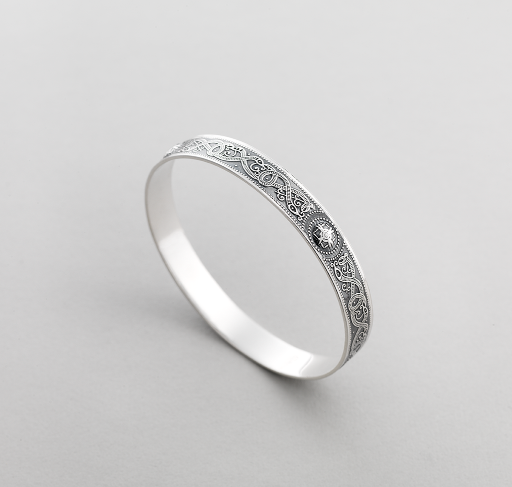 Silver bangle with Celtic design of intertwined serpents.